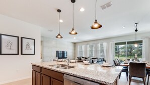 A modern kitchen with granite countertops, stainless steel appliances, and pendant lighting. - 5280oak Luxury Ne 6 Bedroom 4.bath Home (Davenport)