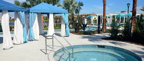 A pool area with a circular pool, blue and white canopies, and palm trees.