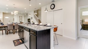 A spacious kitchen with a large island, pendant lighting, and a clock on the wall. - 5 BED 5 Bath Resort Villa (Kissimmee)
