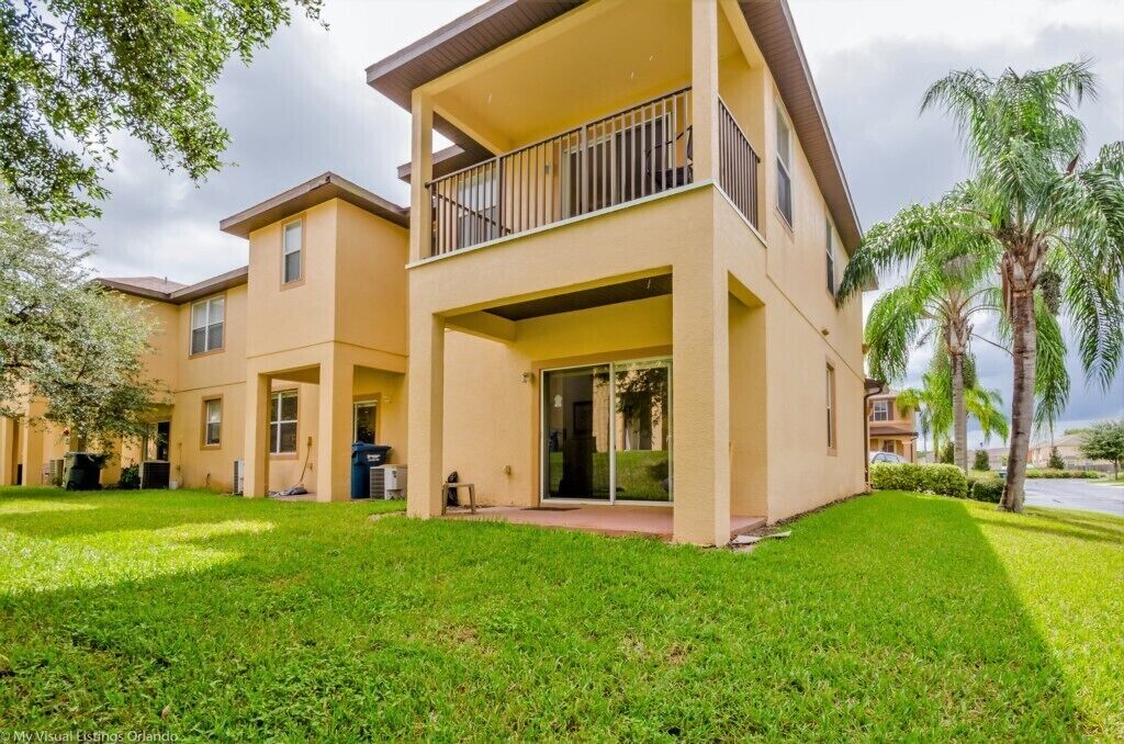 A multi-story building with a flat roof, a balcony on the upper floor, and a well-maintained lawn.
