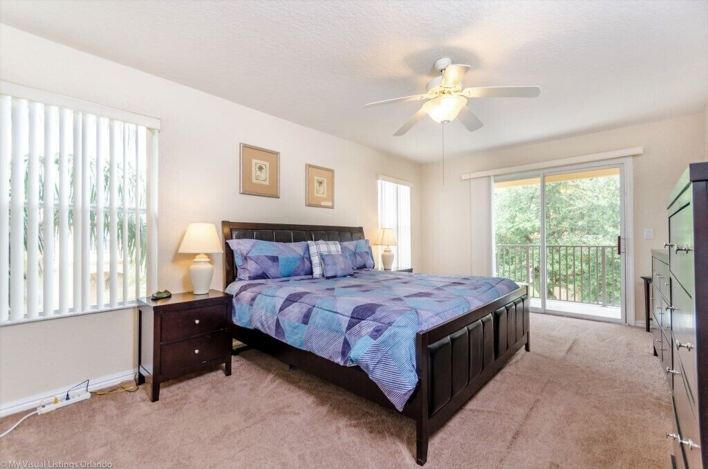 A bedroom with a bed, a ceiling fan, a nightstand, a dresser, and a window with blinds.