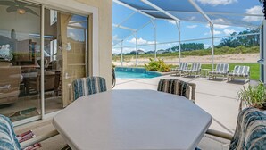 Une terrasse couverte avec une piscine, des sièges d’extérieur et une vue sur la plage.