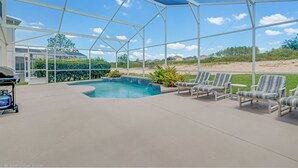Une piscine extérieure couverte, dotée de chaises longues et d’un espace barbecue.
