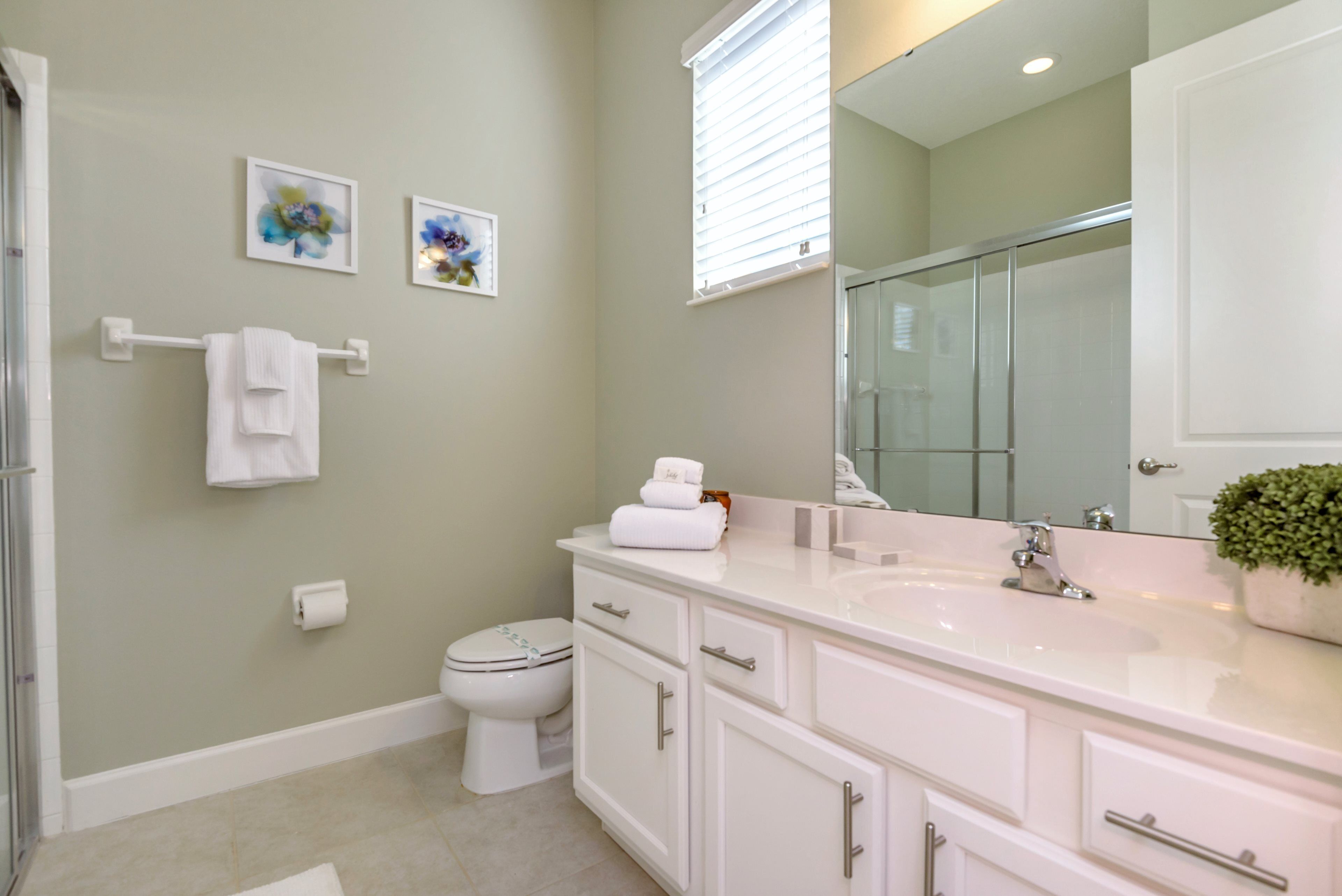 A modern bathroom with a white vanity, a large mirror, and a toilet.