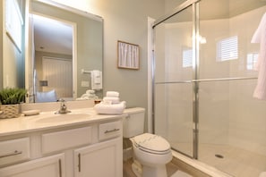 A modern bathroom with a glass shower enclosure, a sink with a mirror, and a toilet. - 5bed 5Ba Reunion Villa W.pool (Kissimmee)