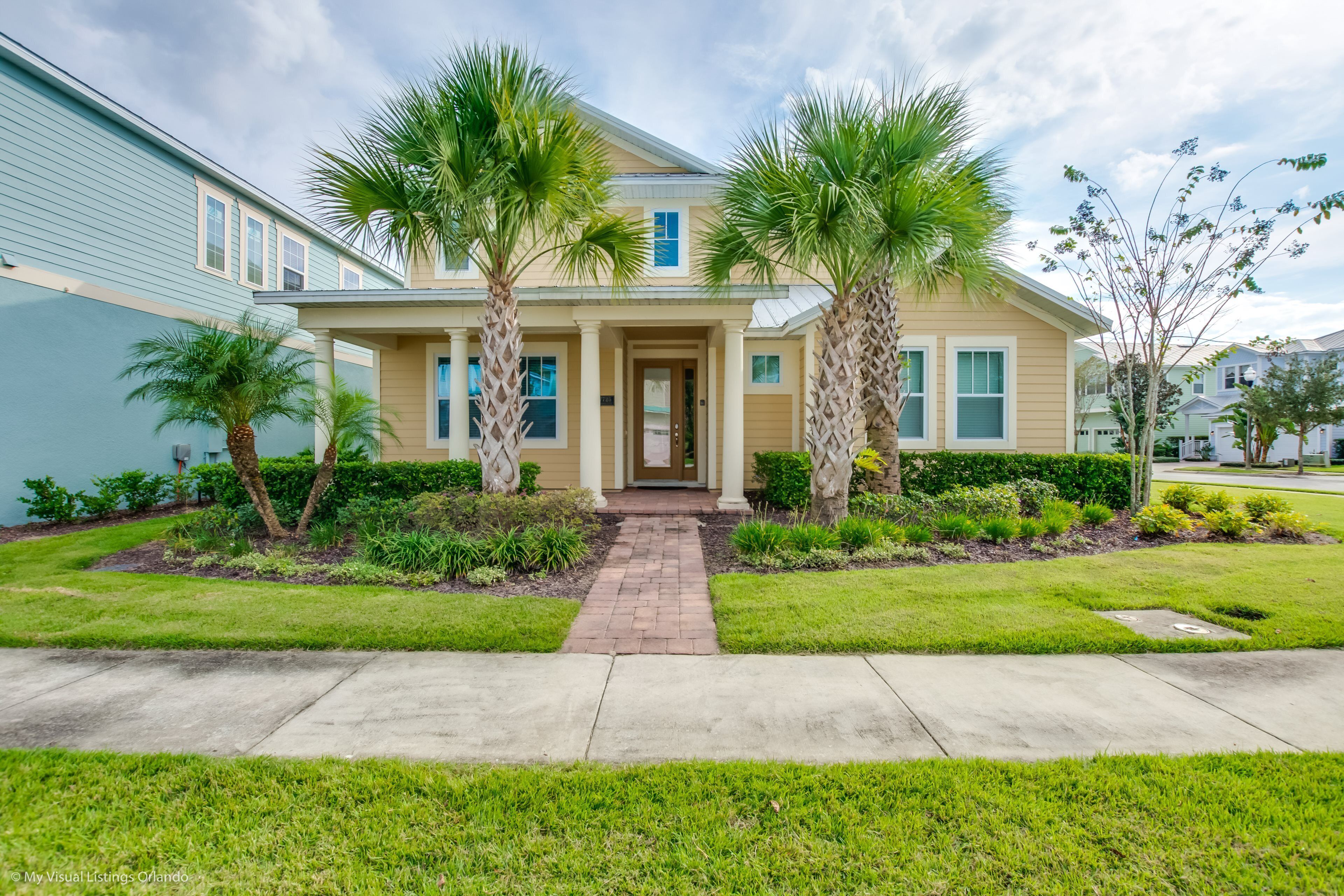 A two-story house with a front porch, palm trees, and a brick pathway leading to the entrance.