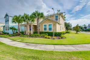 A two-story house with a front yard, palm trees, and a clear sky. - 7725ll Ultimate Reunion Home (Kissimmee)