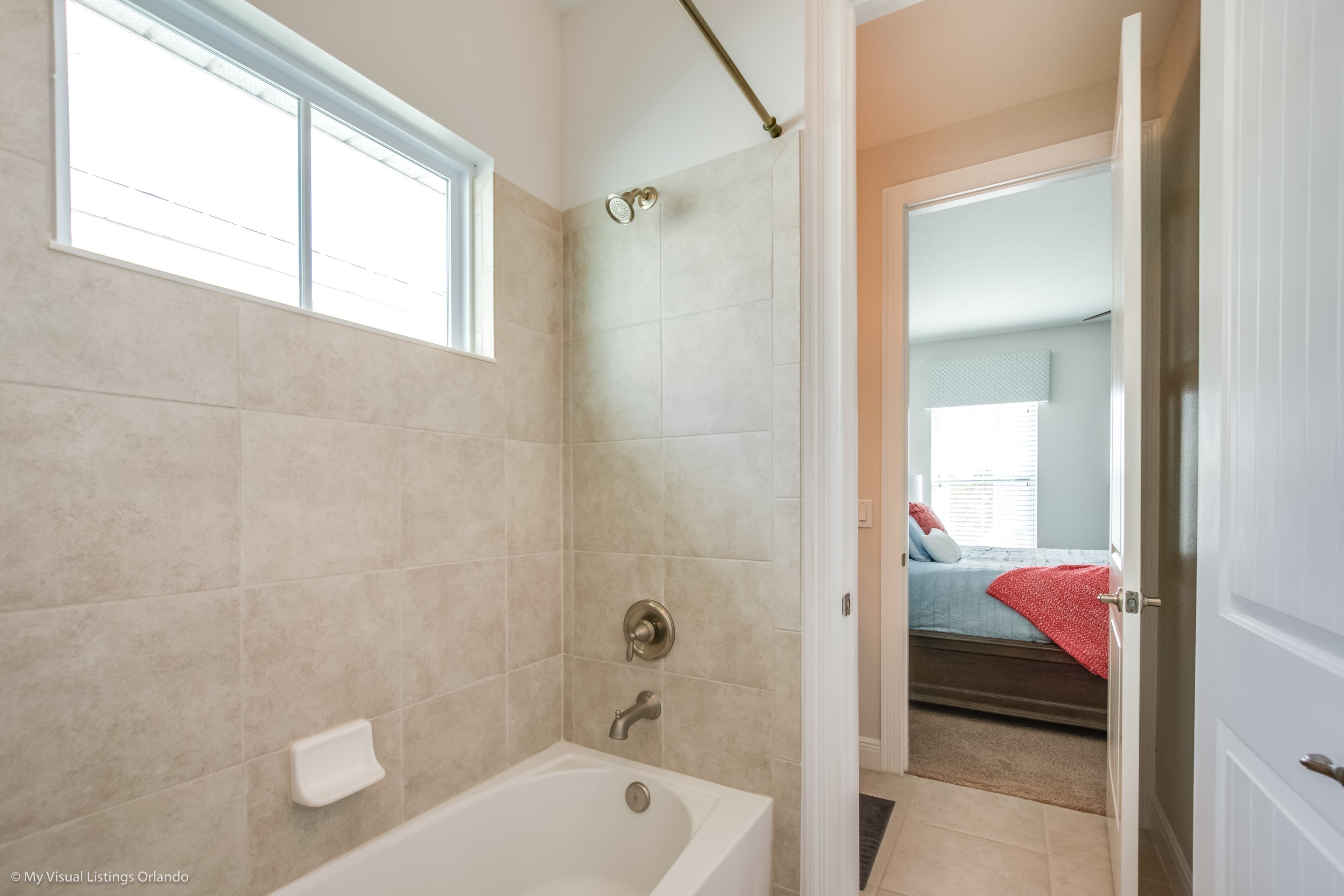Ein Badezimmer mit Badewanne, Dusche und Fenster.