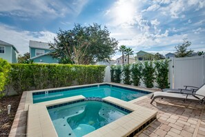 A swimming pool with a hot tub, surrounded by a patio with lounge chairs, and a view of neighboring houses. - 7725ll Ultimate Reunion Home (Kissimmee)