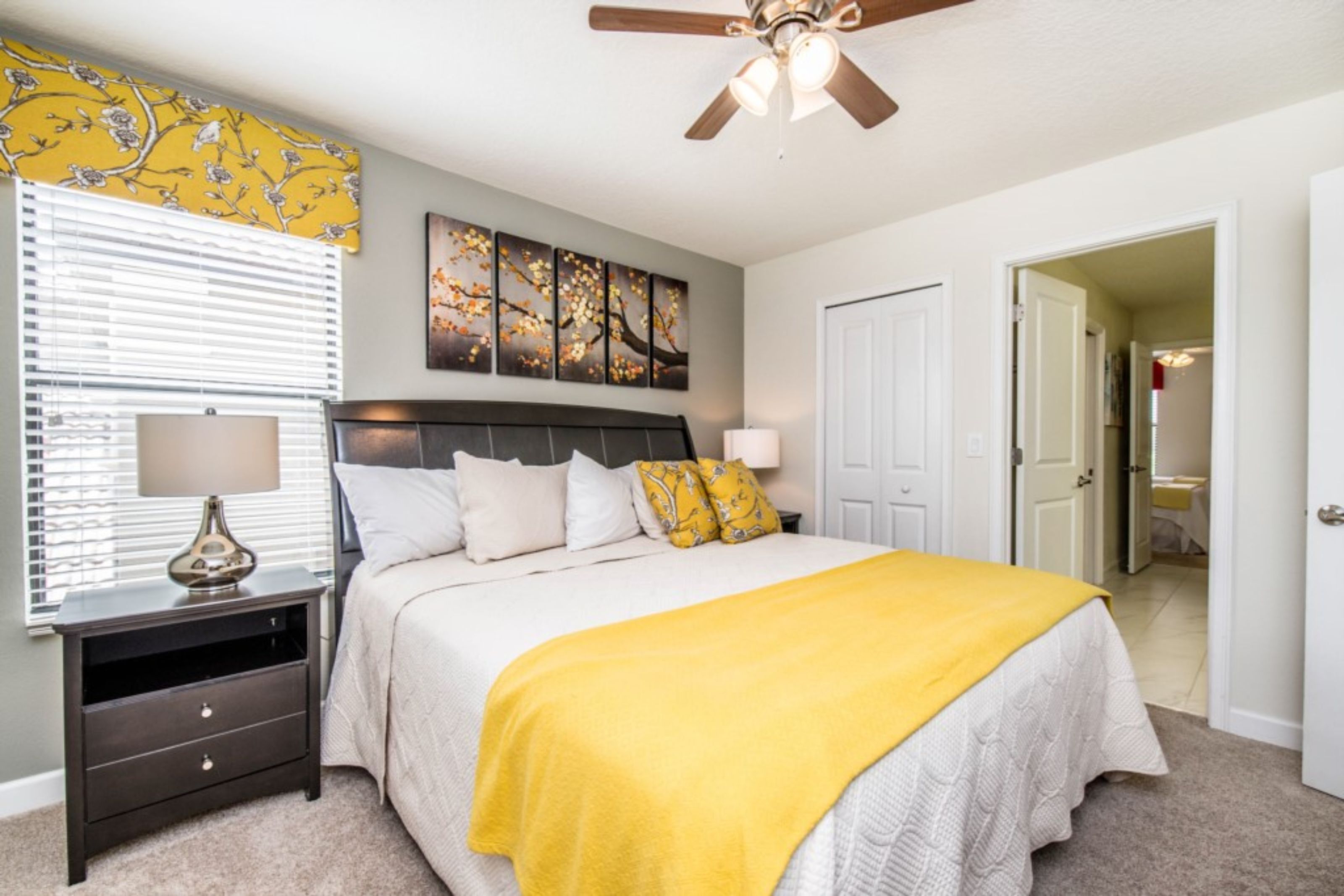 A bedroom with a bed, nightstands, a ceiling fan, and artwork on the wall.