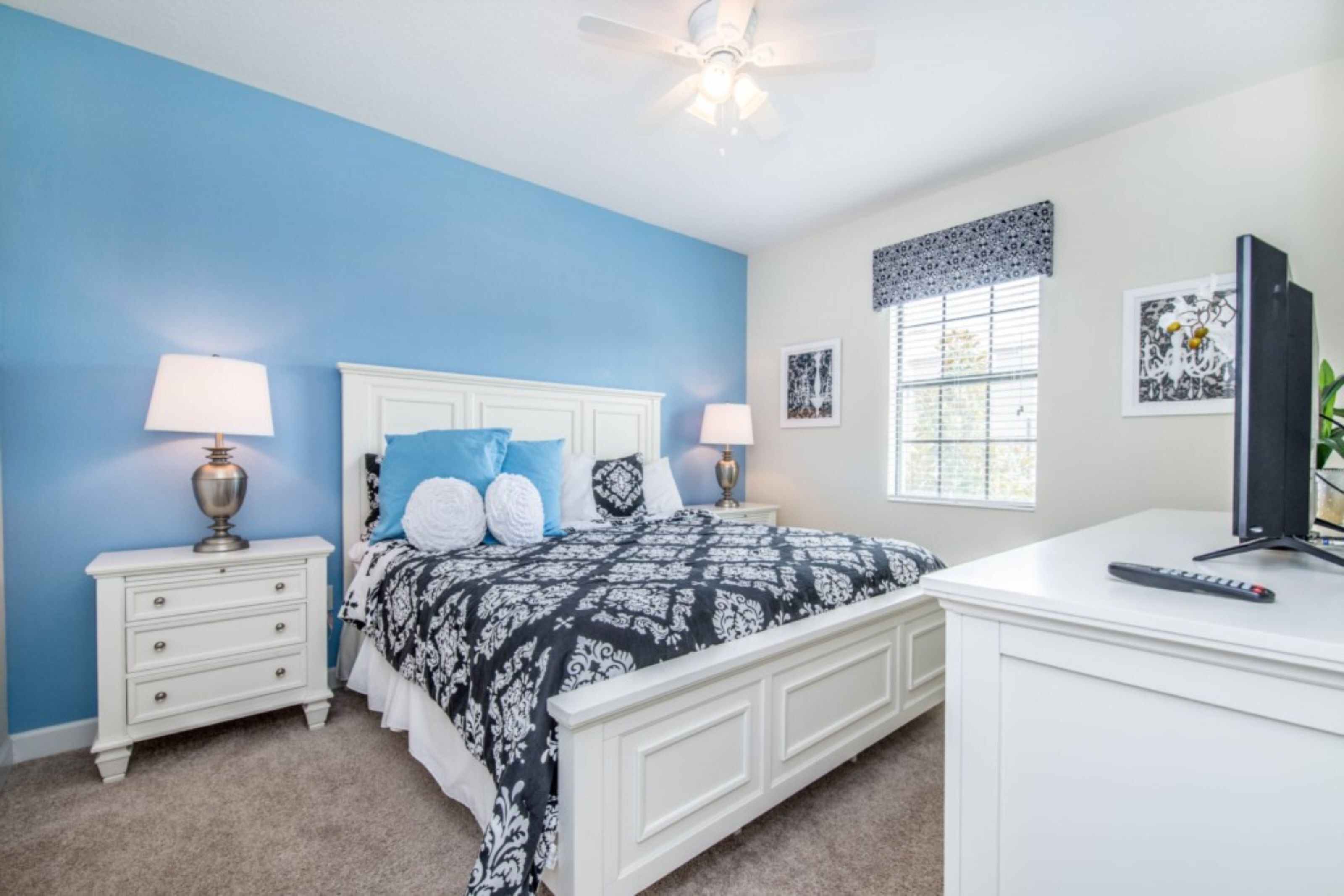 A bedroom with a bed, nightstands, a desk, and a ceiling fan.