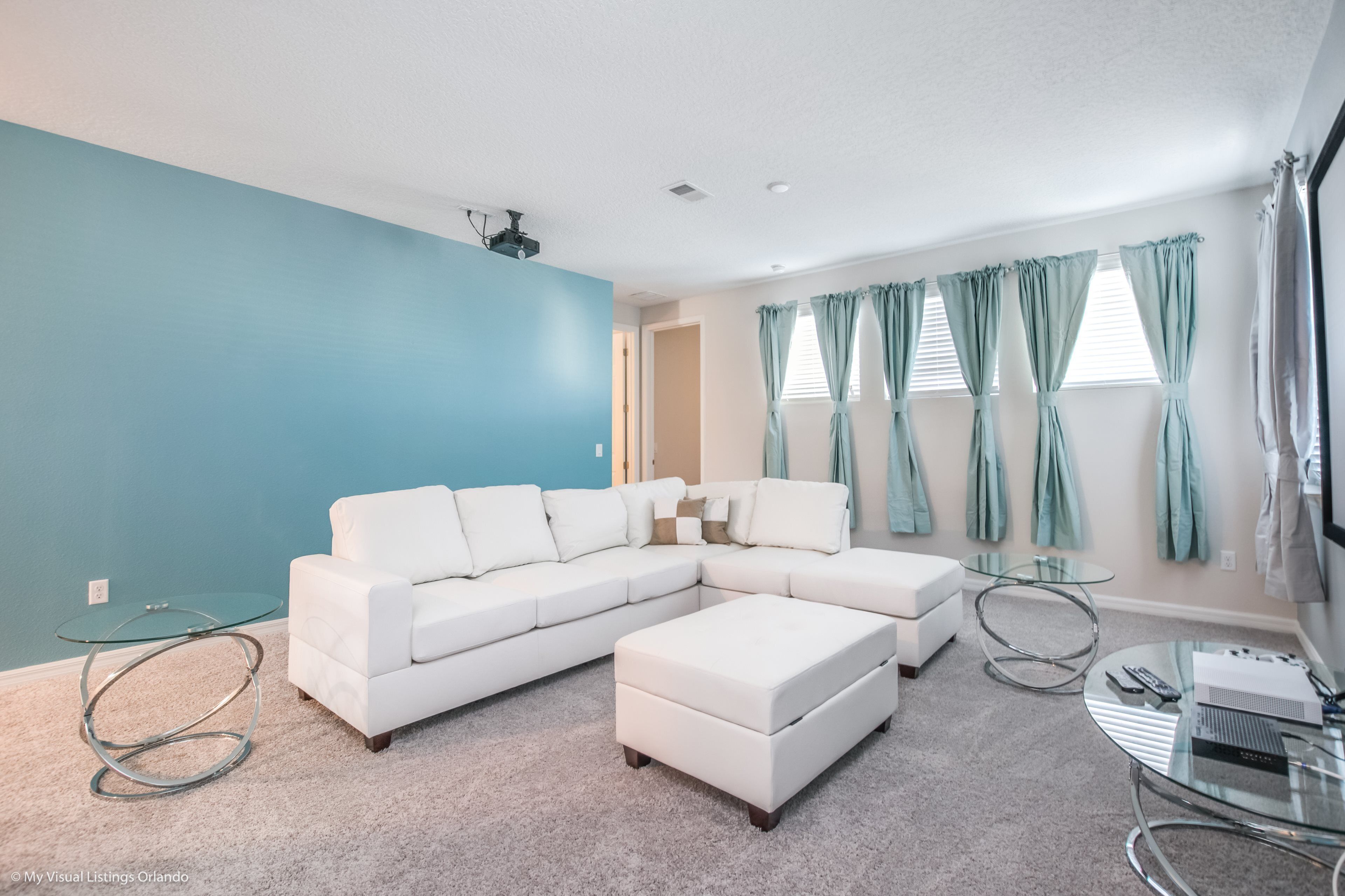 A modern living room with a sectional sofa, a glass coffee table, and a glass side table.