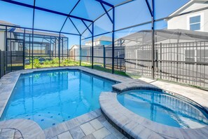A swimming pool with a glass enclosure, surrounded by a fence and a patio area. - 9031 Pelican (Kissimmee)