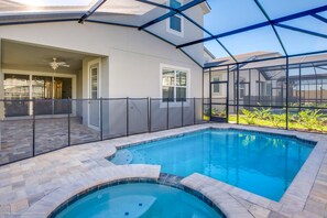 A swimming pool with a glass enclosure, a patio area, and a covered entryway. - 9031 Pelican (Kissimmee)