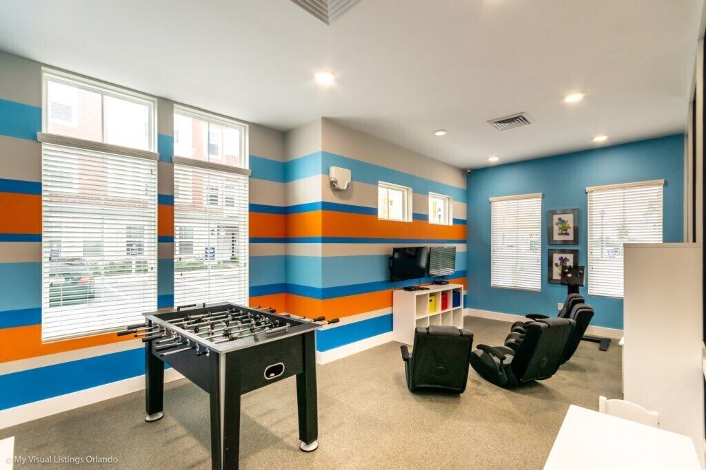 Una habitación con mesa de fútbol de mesa, sillón de masajes y televisor en un estante.