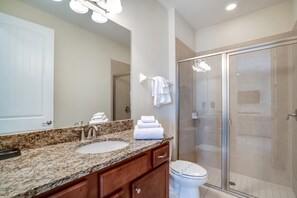 A modern bathroom with a granite countertop sink, a glass shower enclosure, and a white toilet. - Family Friendly 8 Bed Villa with Pool & Spa (Kissimmee)