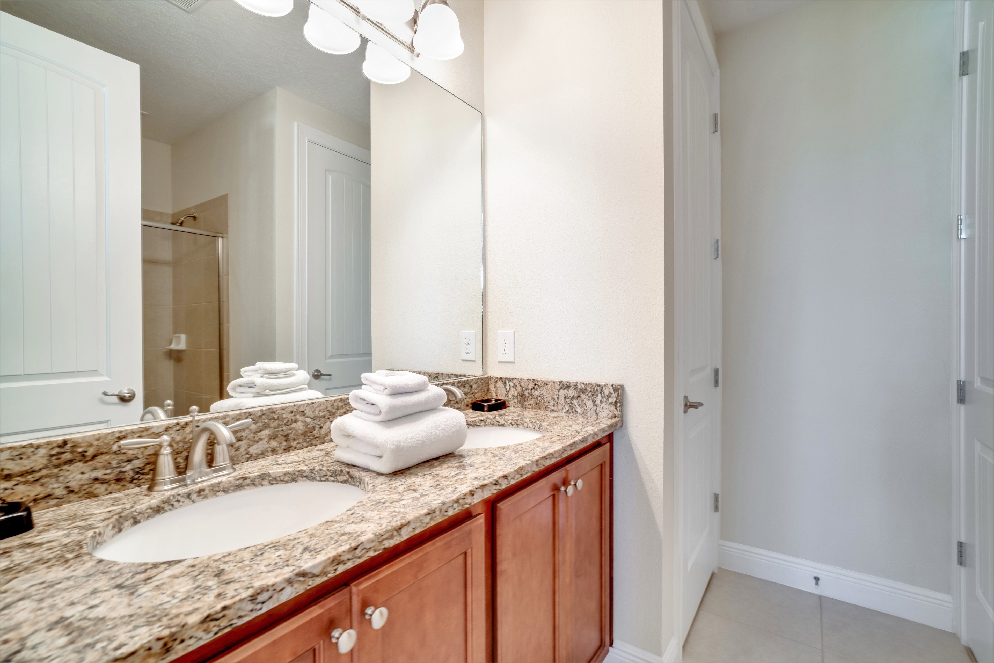 A bathroom with two sinks, a large mirror, and wooden cabinets.