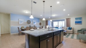 A modern kitchen with a central island, dark cabinetry, and pendant lighting. - 9 Bed Villa with Games, Pool & Spa (Kissimmee)