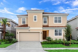 A two-story residential building with a beige facade, a tiled roof, and a garage. - 5300oakb (Davenport)