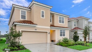 A two-story residential building with a beige exterior, a red-tiled roof, and a garage. - 5300oakb (Davenport)