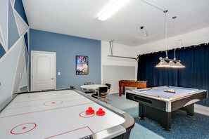 Ett rum med ett biljardbord, ett fotbollsspel och ett bordtennisbord.