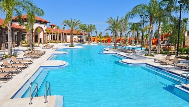 A large swimming pool with multiple lanes, surrounded by palm trees and lounge chairs. - 5300oakb (Davenport)