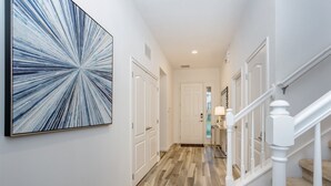 A hallway with a wooden floor, white walls, and a large abstract painting. - 5300oakb (Davenport)