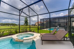 A glass-enclosed outdoor pool area with lounge chairs and a hot tub. - 5300oakb (Davenport)
