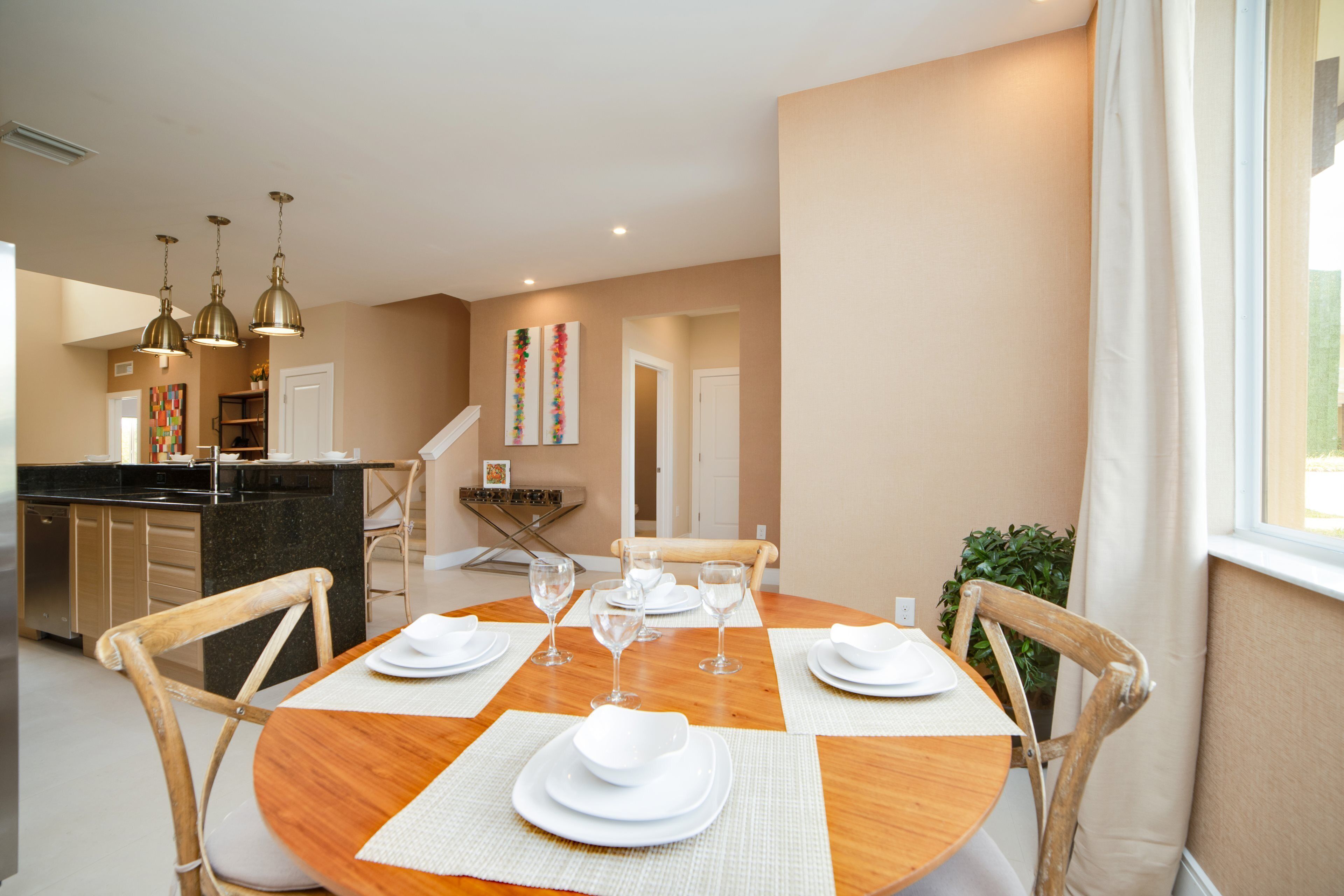 A dining area with a round wooden table set for four, surrounded by wooden chairs.