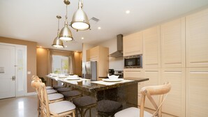 A modern kitchen with a central island, bar stools, and wooden cabinets. - New Magic Villa Resort Townhome 3123bra (Kissimmee)