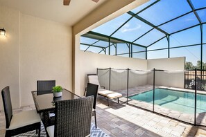 An indoor pool area with a glass enclosure, wicker furniture, and a small table with a plant. - 1515carey (Kissimmee)