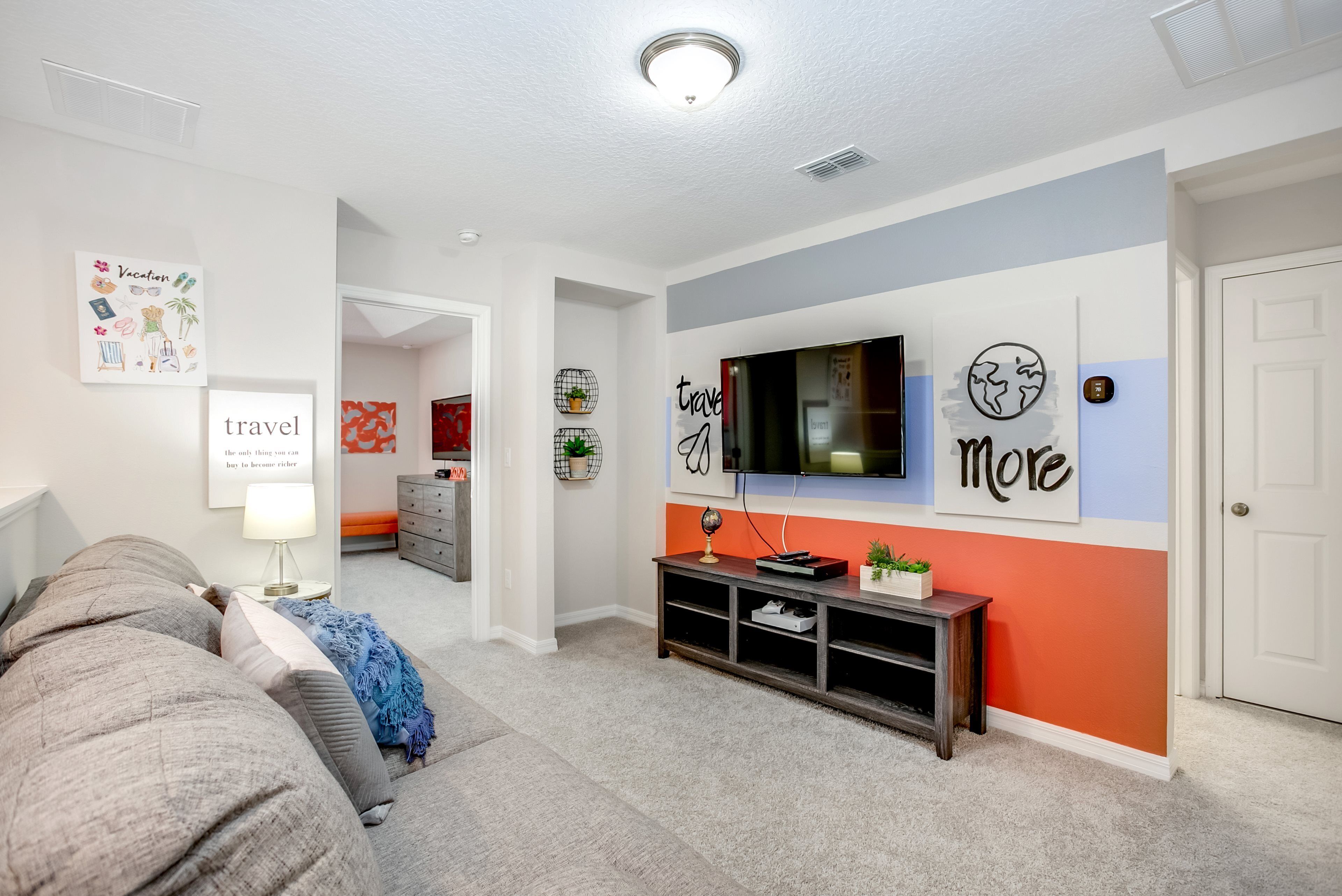 A modern living room with a grey sofa, a TV mounted on the wall, and a console table with decorative items.
