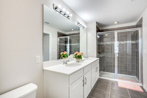 A modern bathroom with a large mirror, two sinks, and a shower enclosure. - 1515carey (Kissimmee)
