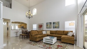 A spacious living room with a large sectional sofa, a coffee table, and a chandelier.