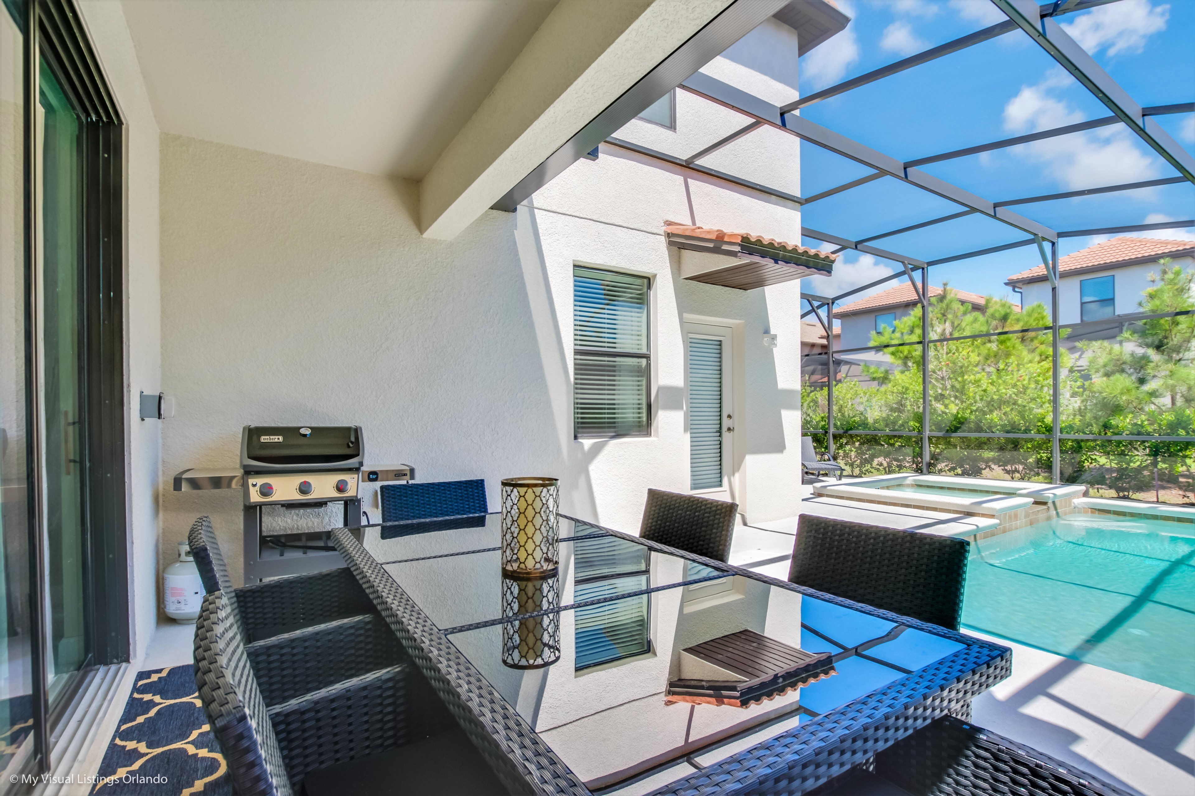 A glass-enclosed balcony with outdoor furniture, a grill, and a pool.