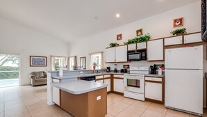 A modern kitchen with white cabinets, a central island, and a built-in oven. - 435castle (Davenport)