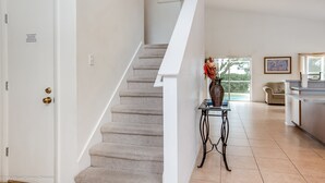 A staircase with a beige carpet, a white wall, and a small table with a vase. - 435castle (Davenport)