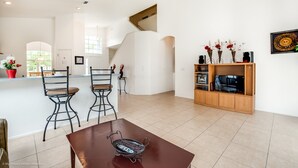 A spacious living area with a dining table, two chairs, a wooden entertainment unit, and a staircase. - 435castle (Davenport)