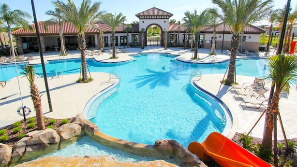 A resort with a large central pool, smaller surrounding pools, palm trees, and a building with a red-tiled roof. - 7008oakwood (Davenport)