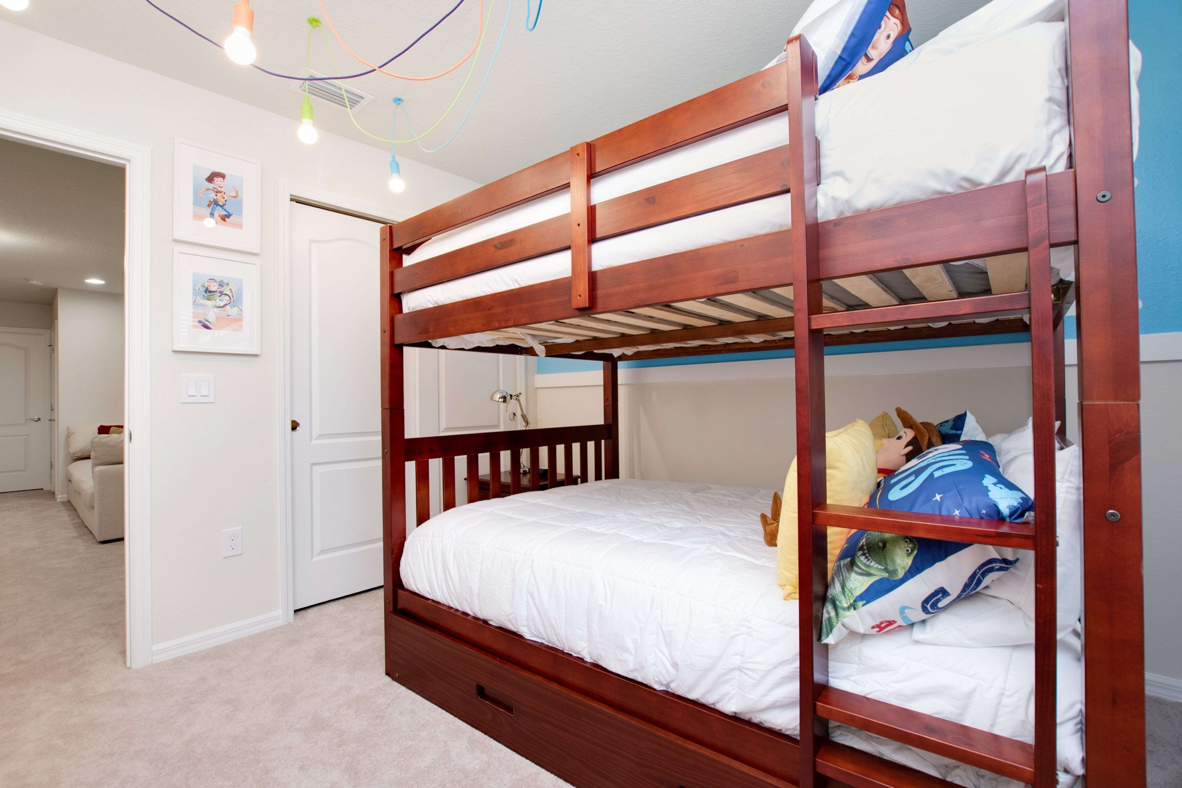 A bunk bed with a wooden frame and white bedding, a white door, and a small hallway with a white couch.