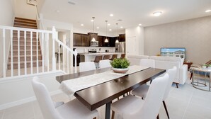 A modern kitchen with dark cabinets, a central island, and pendant lighting. - 5 bed Town Home With Pool (Kissimmee)