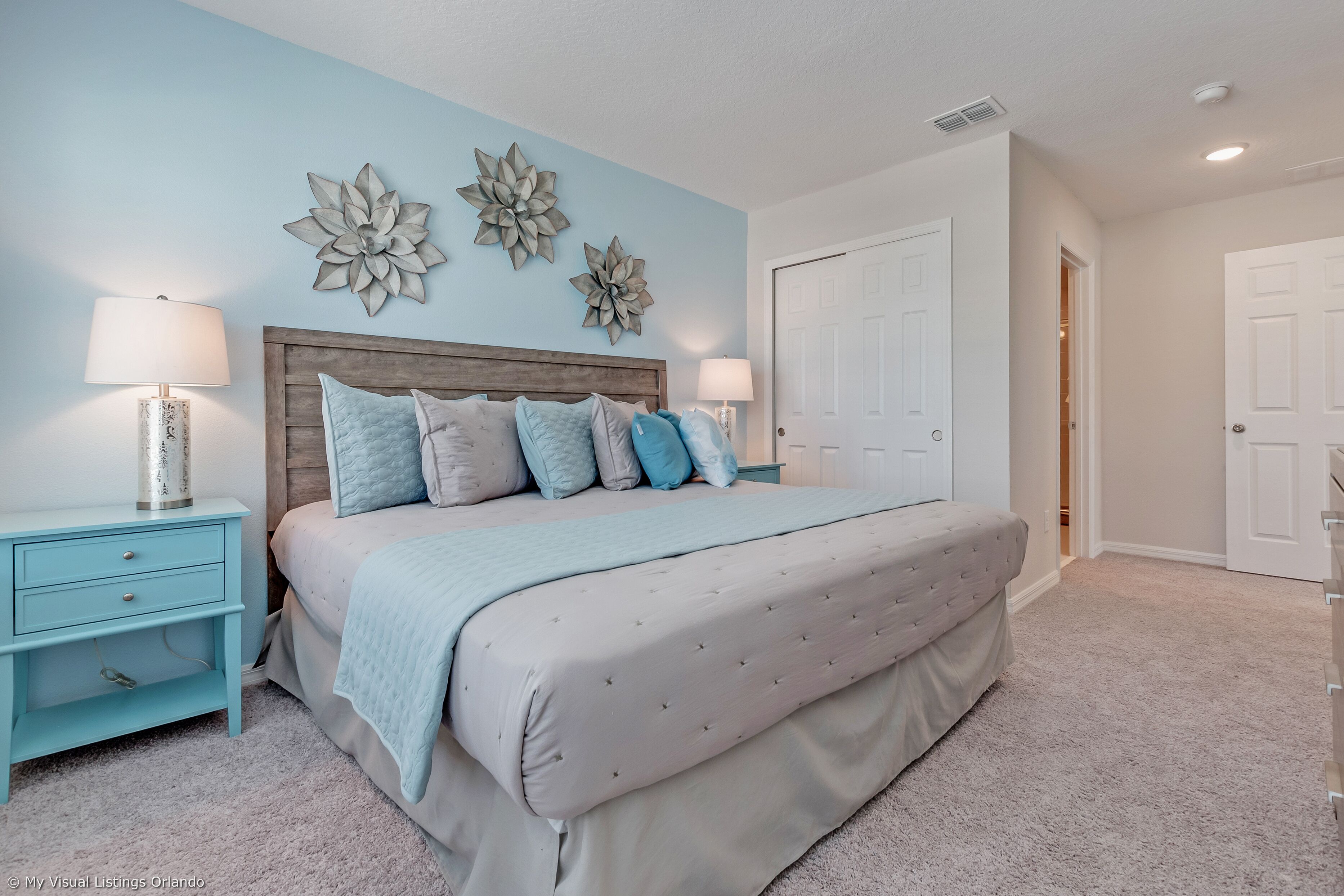 A bedroom with a bed, two nightstands, a headboard, and decorative wall art.