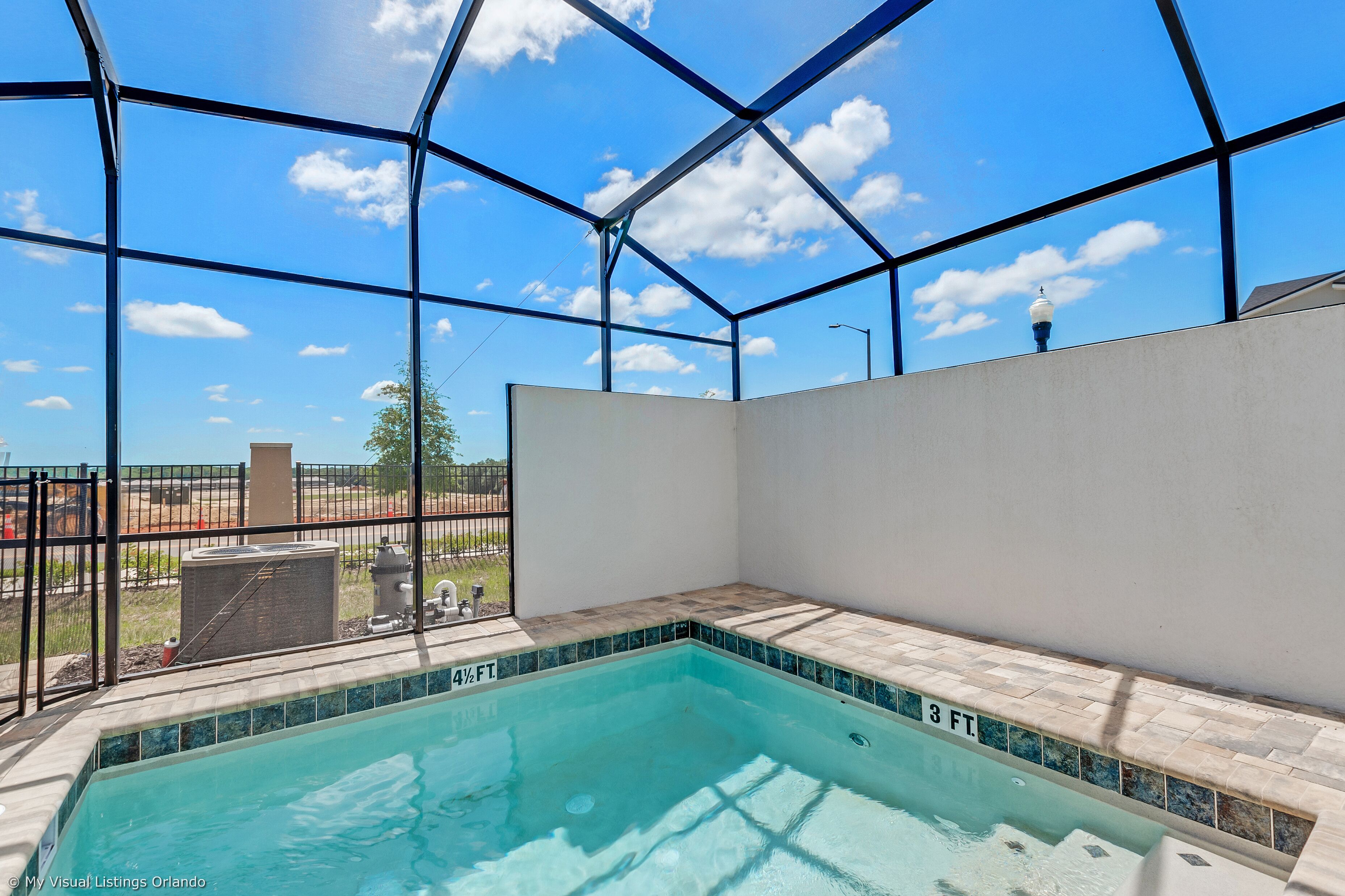 Une piscine à l’eau d’un bleu cristallin, entourée d’une structure en verre et métal.