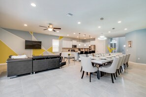 A modern living room with a sofa, dining table, and kitchen in the background. - 8917bengal Sleeps 20 (Kissimmee)