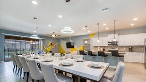 A modern dining area with a large table set for six, surrounded by grey upholstered chairs. - 8917bengal Sleeps 20 (Kissimmee)