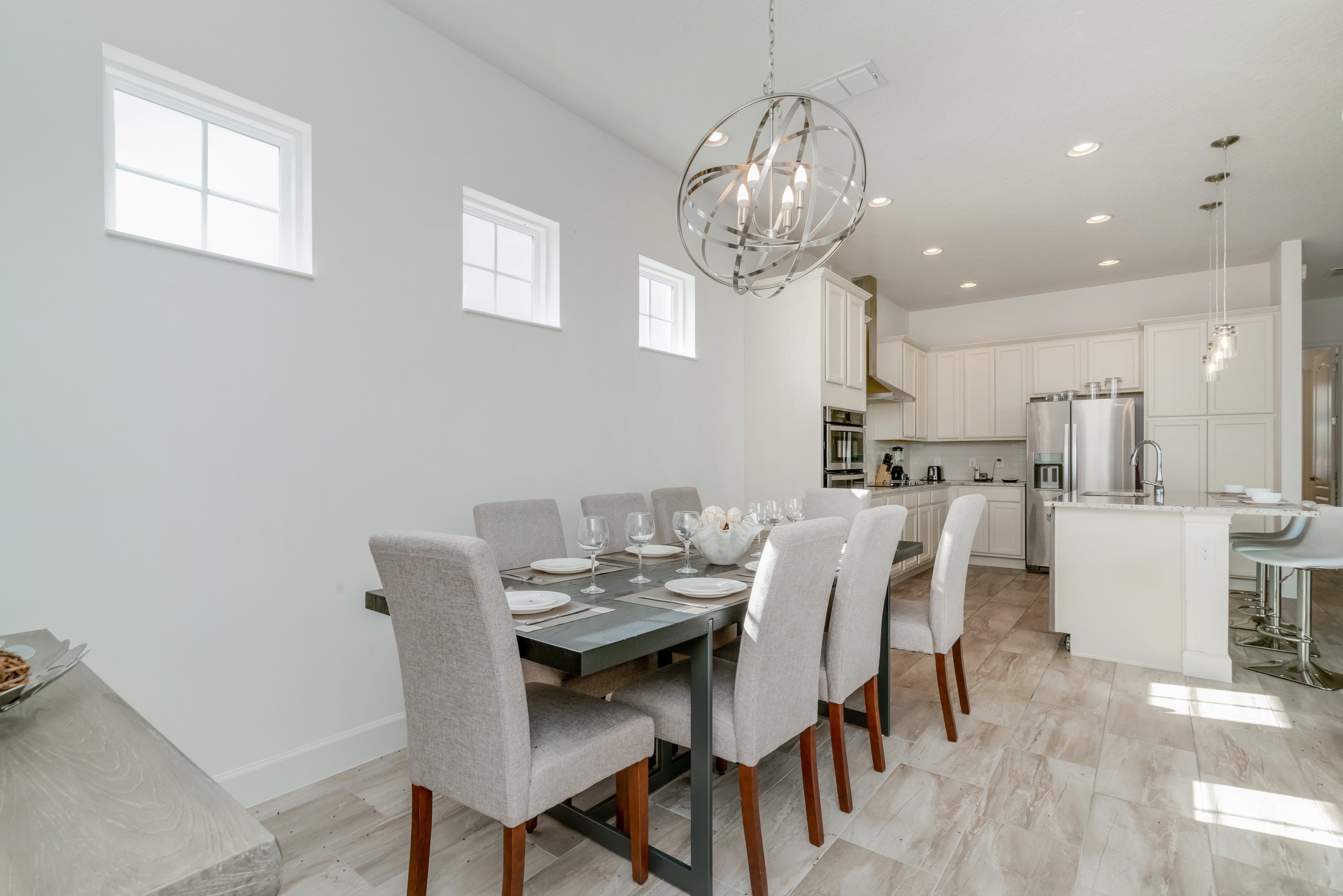 A modern kitchen with white cabinets, a central island, and a dining area with a table set for six.