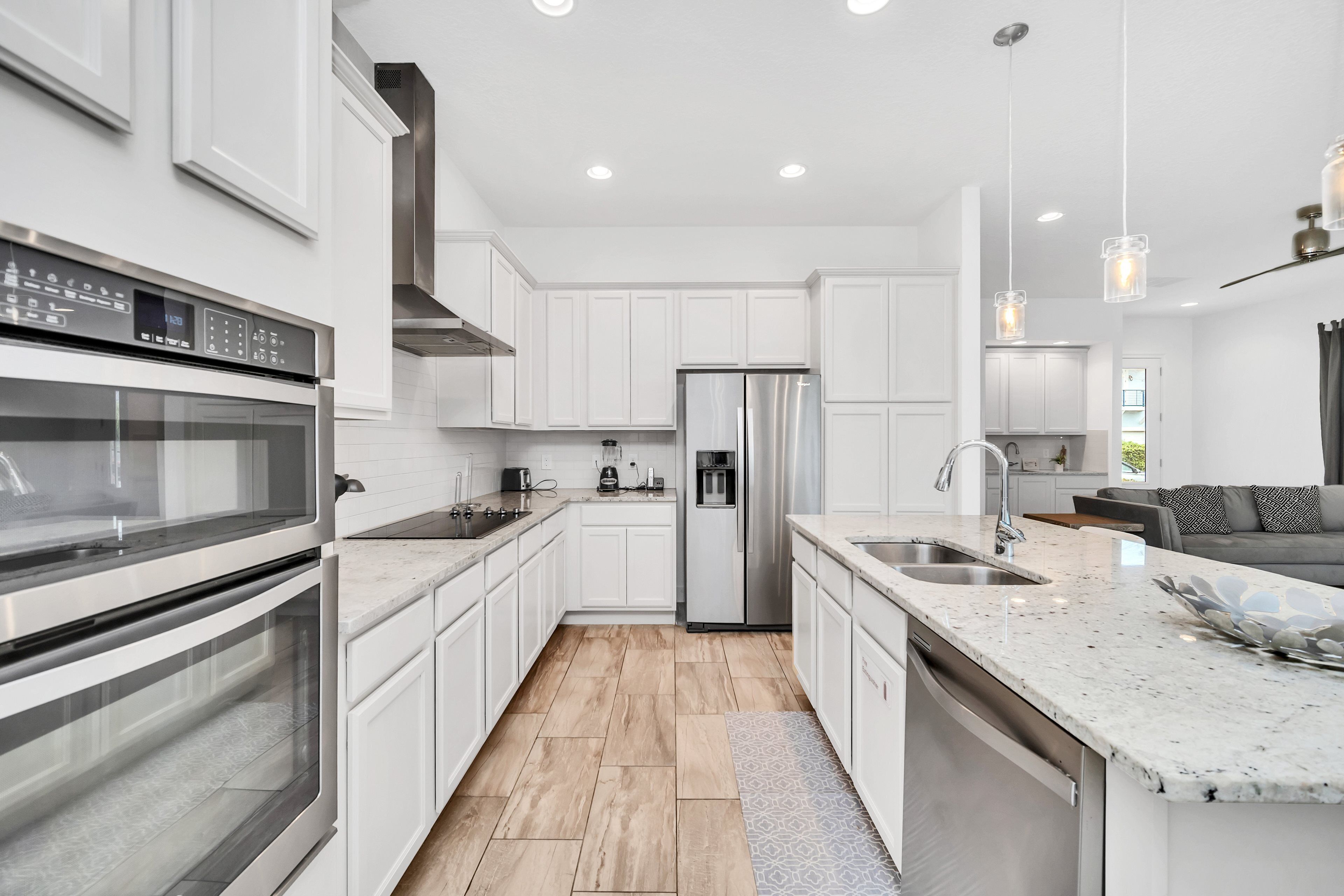 A modern kitchen with white cabinetry, stainless steel appliances, and a marble countertop.