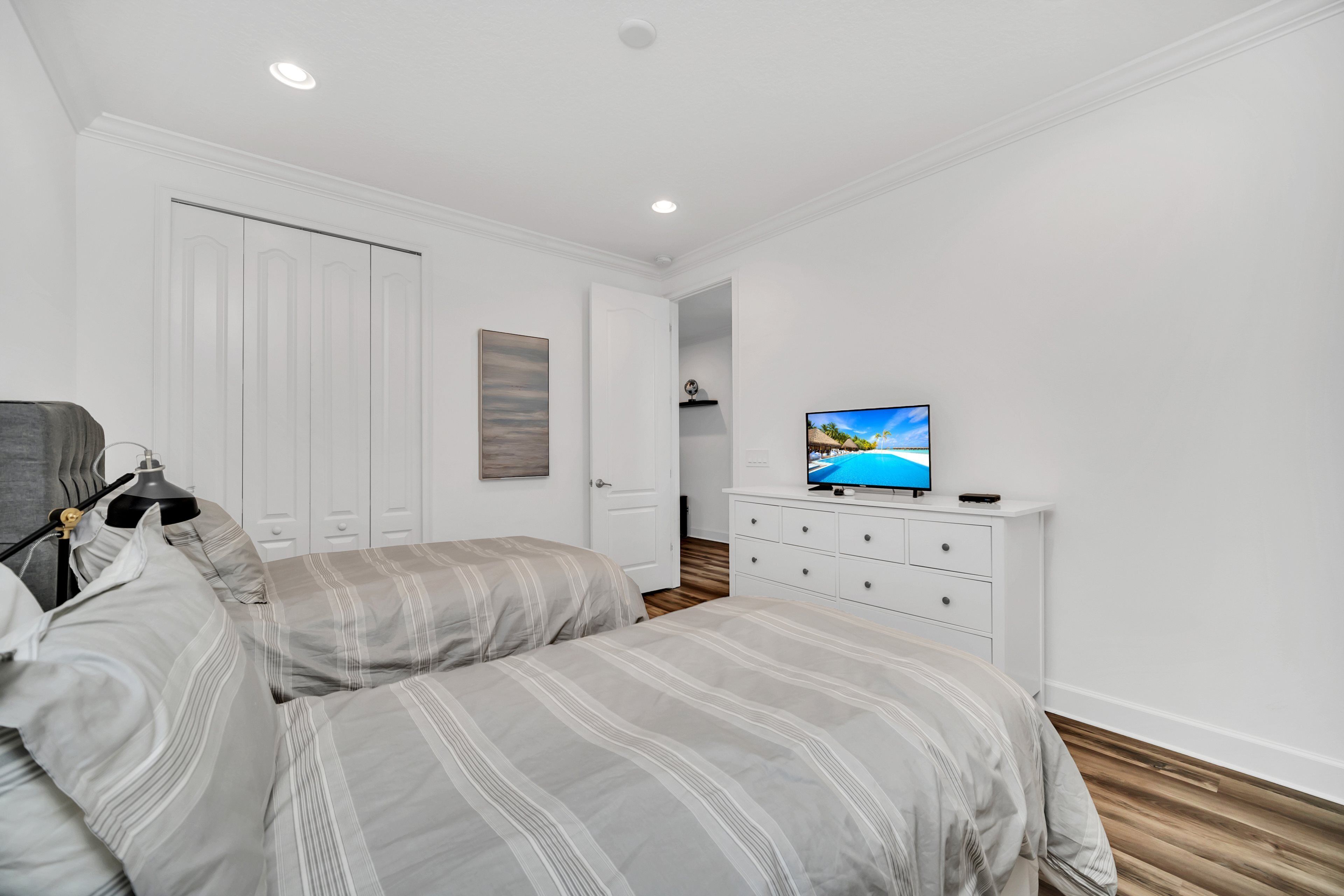 Ein Schlafzimmer mit zwei Betten, einem Schminktisch, einem Fernseher und einem Kleiderschrank.
