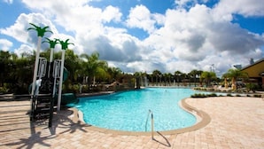 A swimming pool with a curved edge, palm trees, and a clear sky. - 8929bismark (Kissimmee)