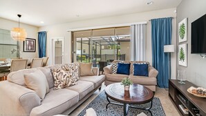 A modern living room with two beige sofas, a coffee table, and a dining area with a table and chairs. - 1939majorca Fantastic 5 Bed 4 Bathroom Town Home (Kissimmee)